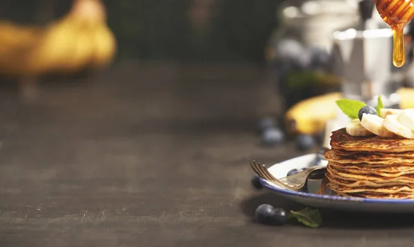 Домашние блинчики со свежими бананами, черникой и медом — стоковое фото
