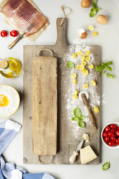 Råa italiensk pasta tortellini på träskiva — Stockfoto