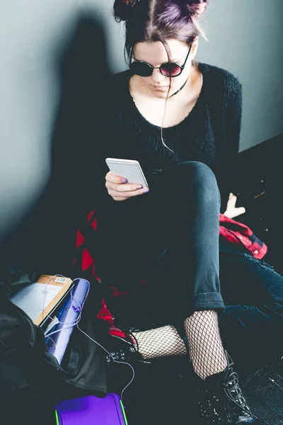 Young alternative girl sitting on the black floor with a school — Stock Photo, Image