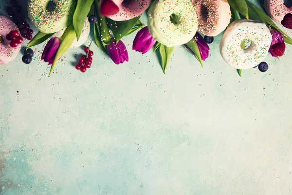 Ciambelle dolci e colorate con spruzzi, tulipani viola e — Foto Stock