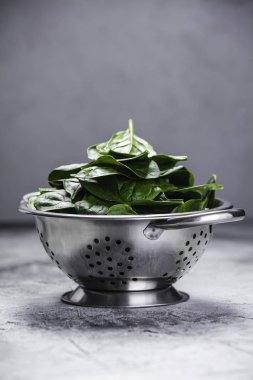 Metal kevgir içinde taze organik ıspanak yaprakları. 