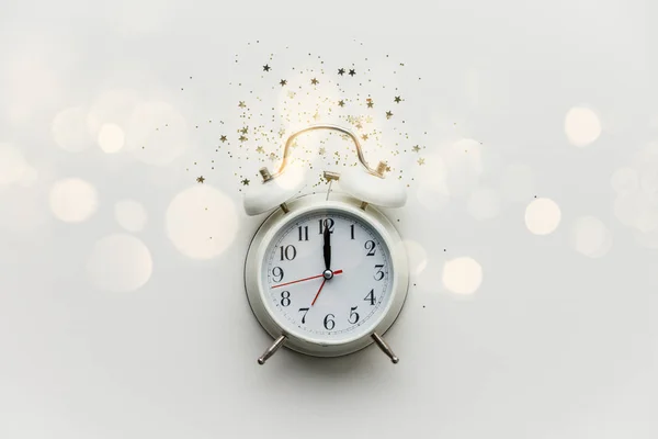 Composición plana con reloj despertador y confeti de estrellas doradas sobre fondo blanco — Foto de Stock