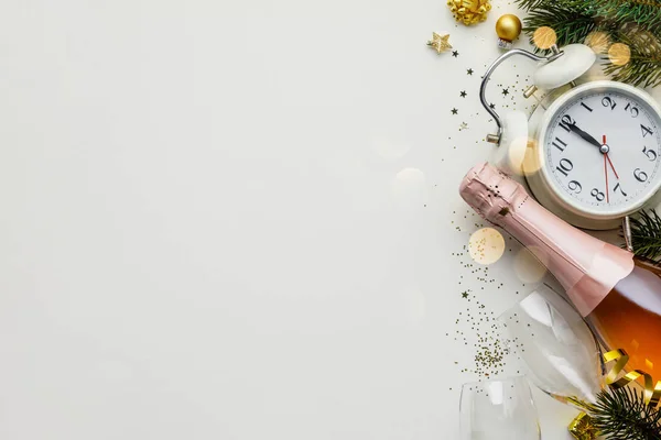 Composição de Natal ou Ano Novo em fundo branco com despertador retro, garrafa de champanhe, copos e decorações de Natal — Fotografia de Stock