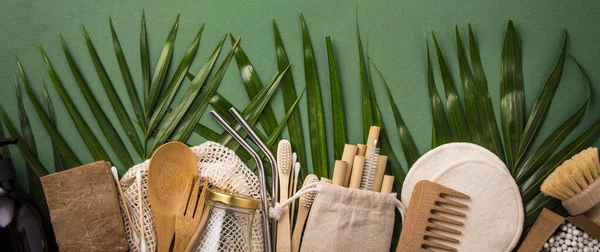 Zero conceito de desperdício. Saco de algodão, talho de bambu, jarra de vidro, escovas de dentes de bambu, escova de cabelo e palhas em fundo verde — Fotografia de Stock