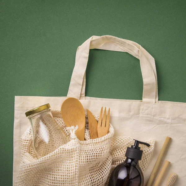 Geen afval concept. Katoenzak, bamboe culterie, glazen pot, bamboe tandenborstels, haarborstel en rietjes op groene ondergrond — Stockfoto