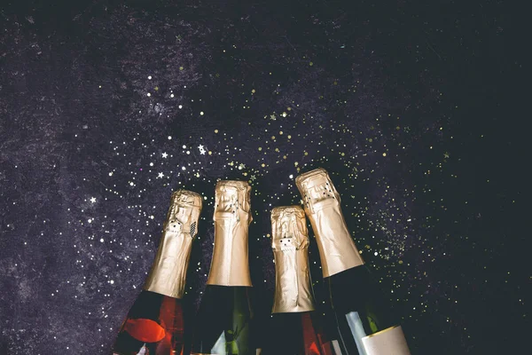 Bottles of champagne with gold glitter and space for text on dark background — Stock Photo, Image