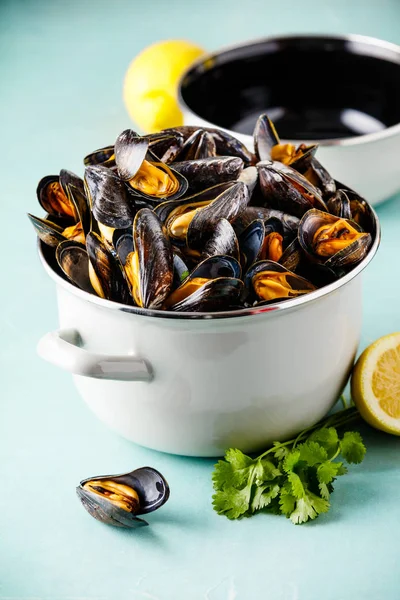 Pot full of steamed mussels on blue background — Stock Photo, Image