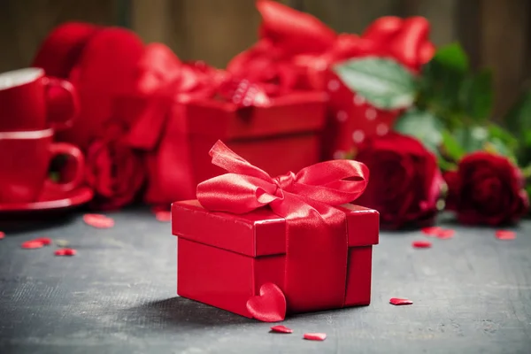 Valentin-napi koncepció. Valentin ajándékdobozok kötött piros szatén szalag íj és gyönyörű rózsák rusztikus háttér. — Stock Fotó