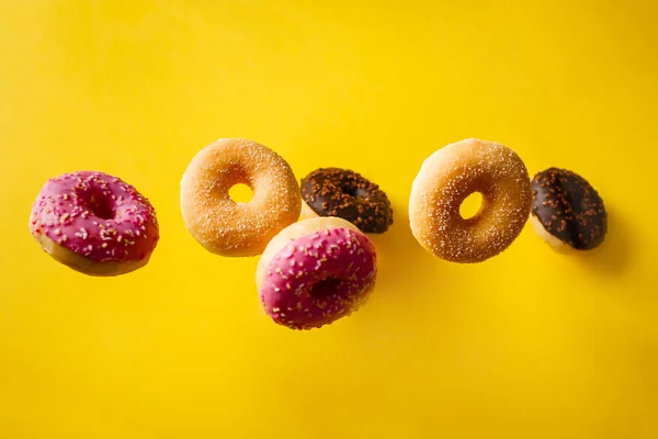 各种装饰的甜甜圈在发黄的背景下运动 — 图库照片