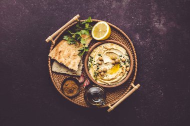 Nohut, kırmızı tatlı biber, maydanoz ve zeytinyağıyla süslenmiş büyük bir kâse ev yapımı humus.