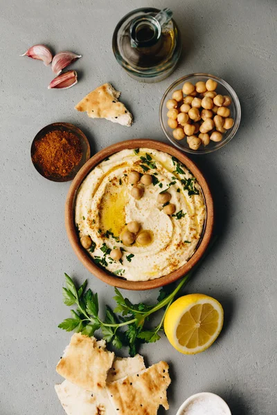 Grande ciotola di hummus fatto in casa guarnito con ceci, peperone rosso dolce, prezzemolo e olio d'oliva — Foto Stock