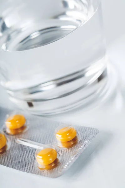 Léky pilulky v blistrech se sklenicí vody — Stock fotografie