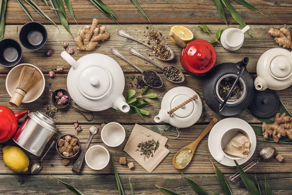 Varios té y teteras composición, hierbas secas, verde, té negro y té matcha sobre fondo de mesa de madera — Foto de Stock
