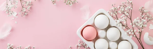 Πασχαλινά αυγά σε λευκό κεραμικό κάτοχο και λουλούδια σε ροζ φόντο — Φωτογραφία Αρχείου