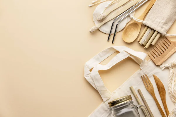 Saco de algodão, talho de bambu, jarra de vidro, escovas de dentes de bambu, escova de cabelo e palhas no fundo de cor, flat lay. — Fotografia de Stock