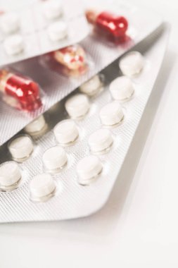 Çeşitli ilaç hapları, haplar ve kapsüller beyaz arka planda.