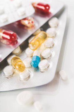 Çeşitli ilaç hapları, haplar ve kapsüller beyaz arka planda.