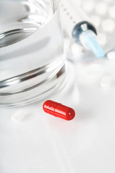 Pastillas y cápsulas medicinales con vaso de agua sobre fondo blanco . — Foto de Stock