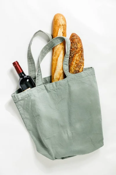 Fresh baguette and bottle of wine in cotton bag. Bakery Products. Friendly packaging.