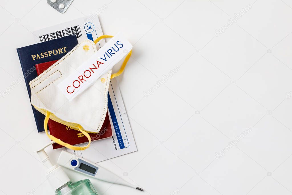 Coronavirus and travel concept. Passports, airplane tickets, sanitizer, thermometer and medical mask flat lay