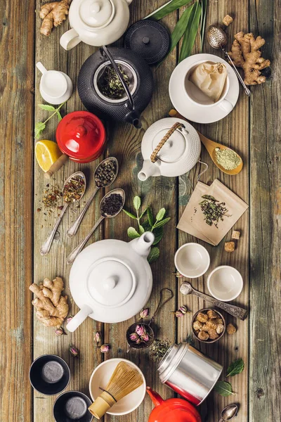 Varios té y teteras composición, hierbas secas, verde, té negro y té matcha sobre fondo de mesa de madera — Foto de Stock