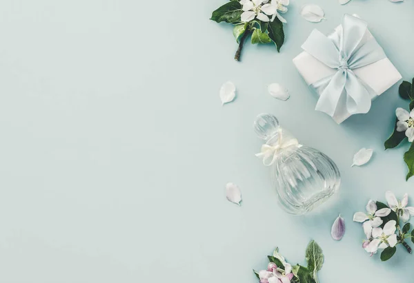 Piękne butelki perfum i wiosenne kwiaty na niebieskim tle — Zdjęcie stockowe