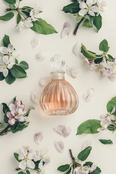 Schöne Parfümflaschen und Frühlingsblumen auf weißem Hintergrund — Stockfoto