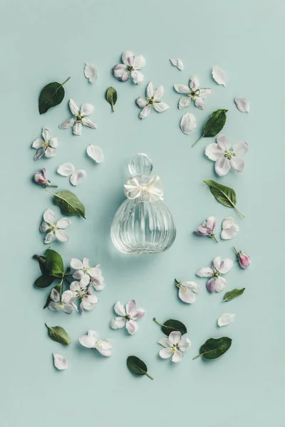 Όμορφα μπουκαλάκια αρωμάτων και ανοιξιάτικα λουλούδια σε μπλε φόντο — Φωτογραφία Αρχείου