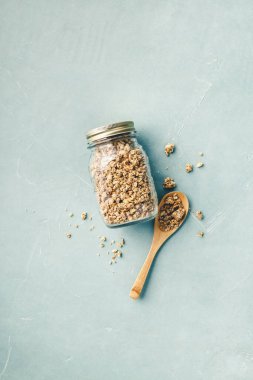 Mavi beton arka planda cam bir kavanozda ev tahılları