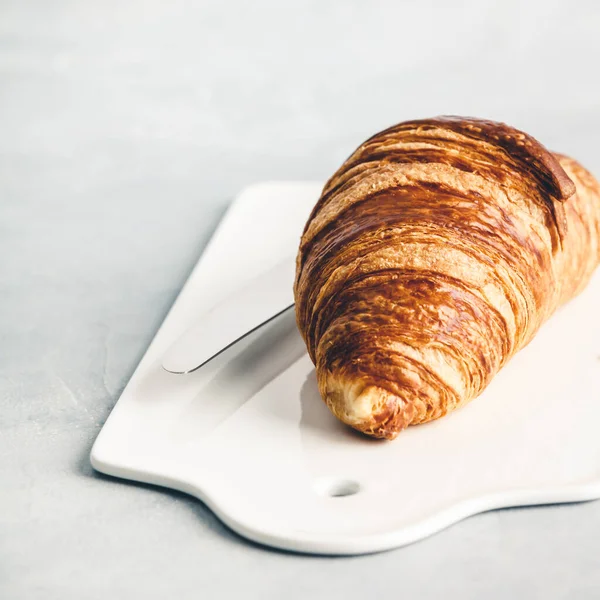 Fresh croissant on white ceramic board, close up — Stock Photo, Image
