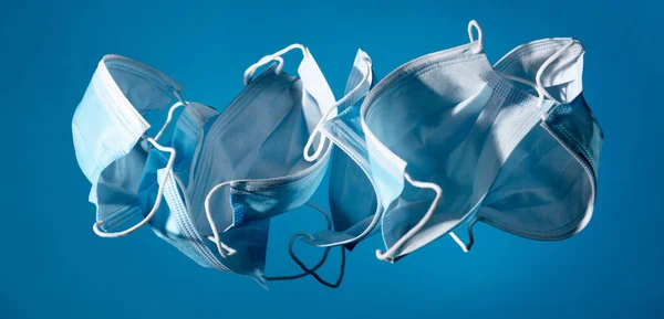 Fliegende Masken auf blauem Hintergrund - Mundschutz, Virus, Grippe, Coronavirus, COVID-19. Medizinische Geräte. — Stockfoto