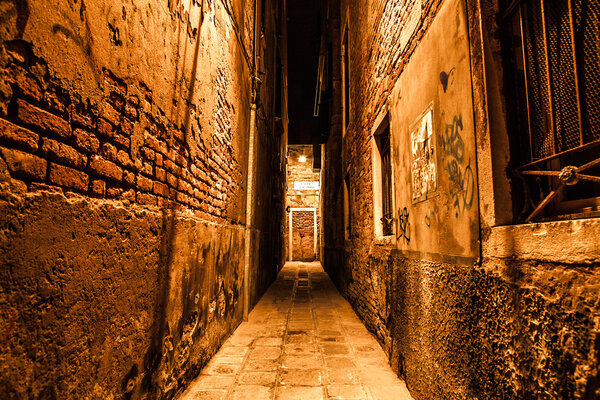 Ancient narrow streets and facades of old medieval buildings at night time close-up. Venice, Italy.