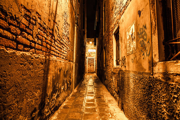 Ancient narrow streets and facades of old medieval buildings at night time close-up. Venice, Italy.