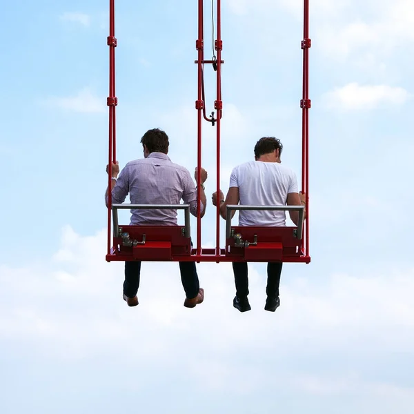 Les gens s'amusent Dans le carrousel swing contre le ciel bleu — Photo