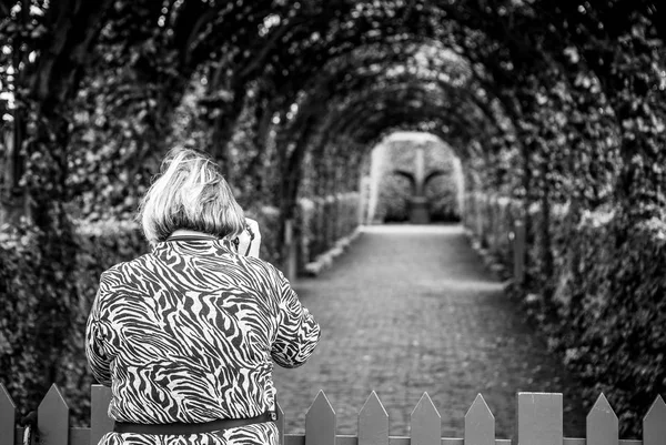 Photo of old woman which photographs park. Muiderslot castle ancient park ensemble in Muiden, Noord-Holland, The Netherlands. — Stock Photo, Image