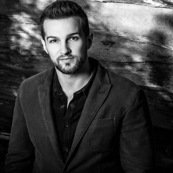 Retrato blanco y negro del joven guapo hombre de moda contra la pared de madera . — Foto de Stock