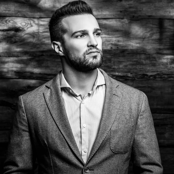 Black-white portrait of young handsome fashionable man against wooden wall. — Stock Photo, Image