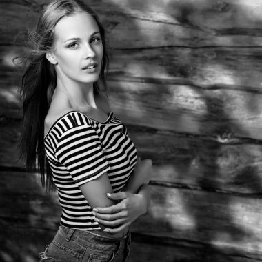 Genç seksi ve güzel sarışın kadın ahşap arka plan üzerinde poz. Siyah-beyaz fotoğraf.