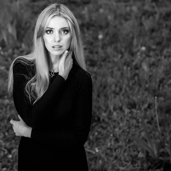 Retrato al aire libre blanco y negro de una hermosa joven rubia sonriente en un vestido elegante . — Foto de Stock