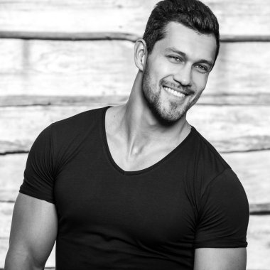 Siyah-beyaz siyah t-shirt ahşap duvar karşı genç güzel sportif adam portresi.