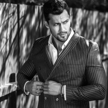 Klasik gri takım elbise teşkil ahşap çit yakınındaki zarif yakışıklı adam.