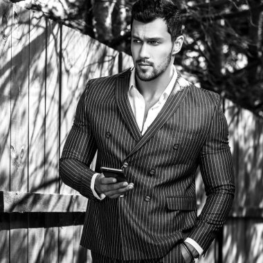 Siyah-beyaz açık ahşap yakınındaki klasik gri elbiseli şık yakışıklı adam portresi 