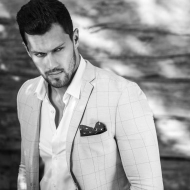 Siyah-Beyaz ahşap duvar karşı beyaz elbiseli genç yakışıklı şık adam portresi