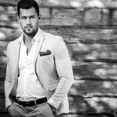 Siyah-Beyaz ahşap duvar karşı beyaz elbiseli genç yakışıklı şık adam portresi