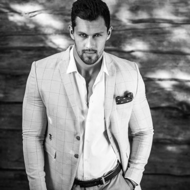 Siyah-Beyaz ahşap duvar karşı beyaz elbiseli genç yakışıklı şık adam portresi