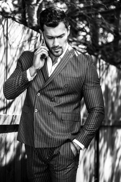 Retrato al aire libre blanco y negro de elegante hombre guapo en traje gris clásico cerca de madera — Foto de Stock