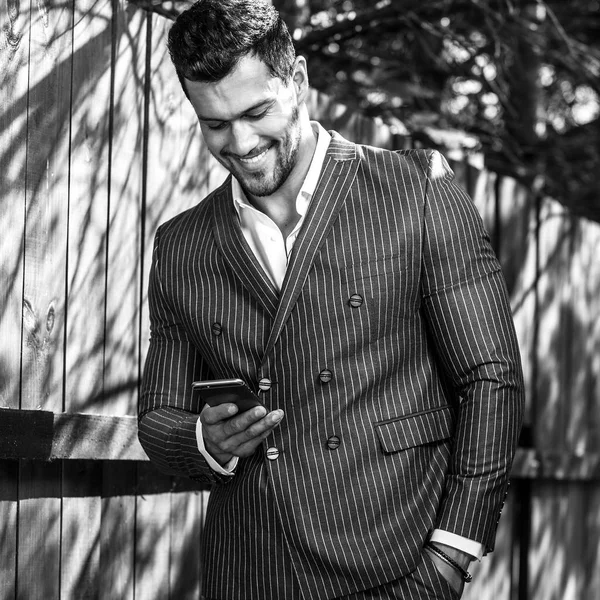 Retrato ao ar livre preto-branco de homem bonito elegante em terno cinza clássico perto de madeira — Fotografia de Stock