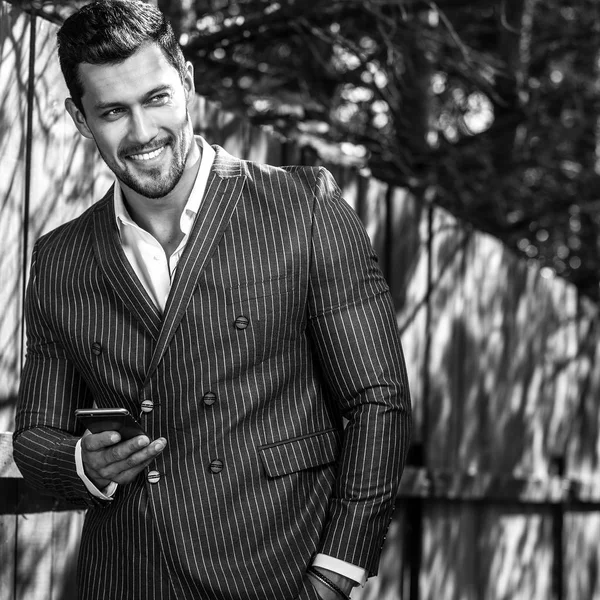 Black-white outdoor portrait of elegant handsome man in classical grey suit near wooden — Stock Photo, Image