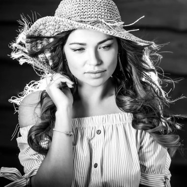 Eski ahşap duvar karşı klasik şapkalı güzel genç kadın portresi siyah-beyaz.