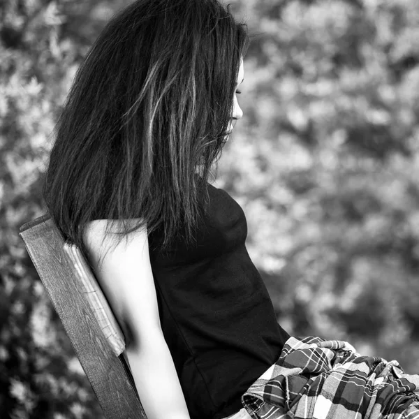 Черно-белый наружный портрет сидящей красивой молодой брюнетки . — стоковое фото